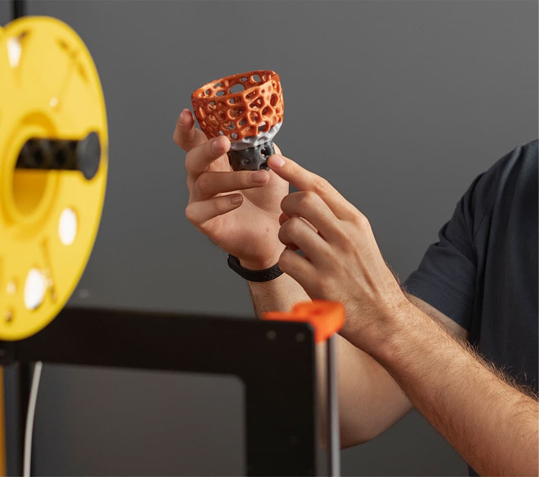 A man is using a DMI 3D printer to make a cup.