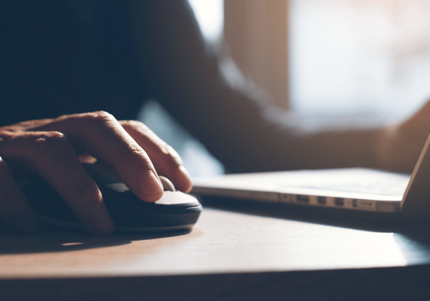 Person clicking mouse in dark office setting